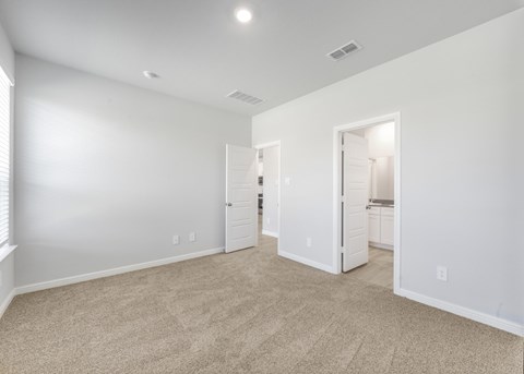 A spacious room with beige carpeting and white walls.