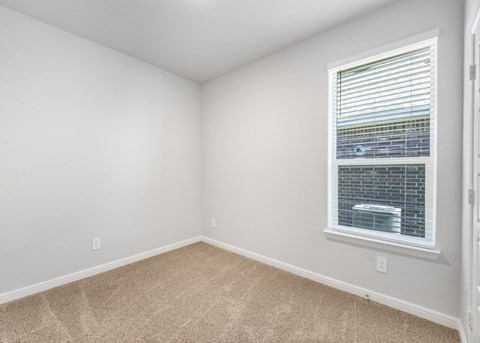 A room with a window and carpeted floor.