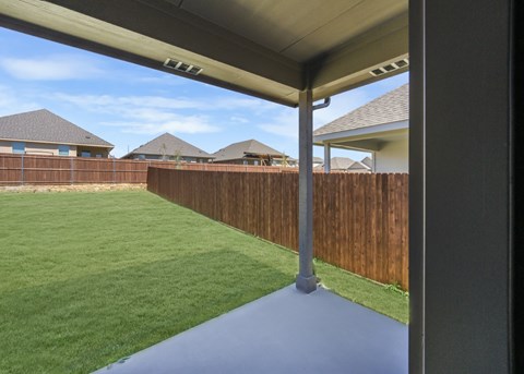 A view from a covered walkway looking out to a grassy yard and houses.