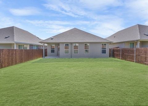 A backyard with a green lawn and three houses.