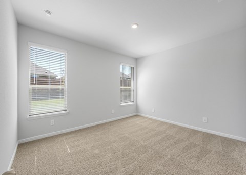 A sparsely furnished room with two windows.