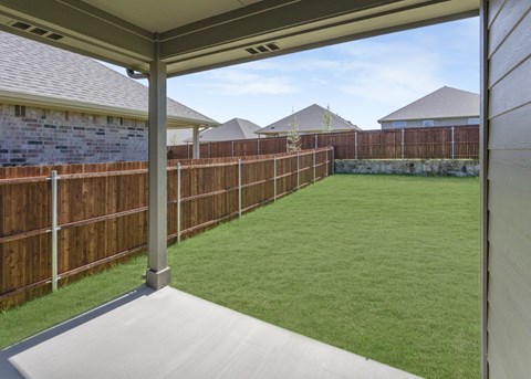 A backyard with a wooden fence and a green lawn.