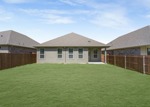 A house with a brown fence and a green lawn.