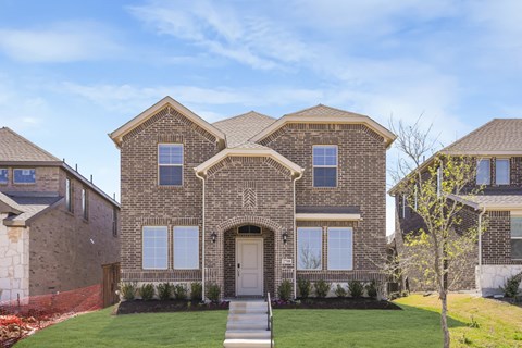 A large house with a front yard and a tree.