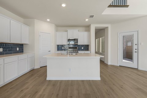 A kitchen with white cabinets and a wooden floor.