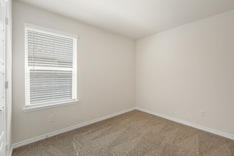 A room with a window and carpeted floor.