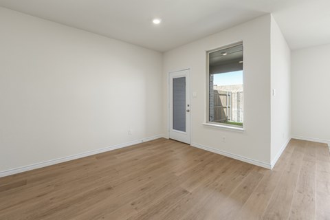 A room with a wooden floor and a window with a view of a building outside.