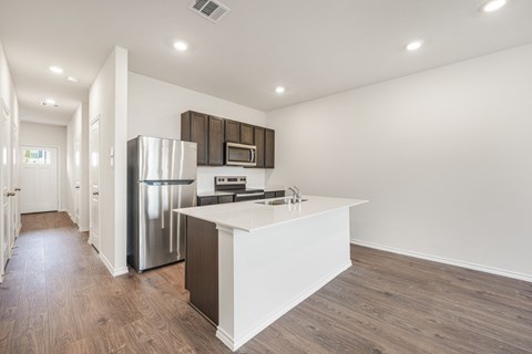 A modern kitchen with a white island and stainless steel appliances.