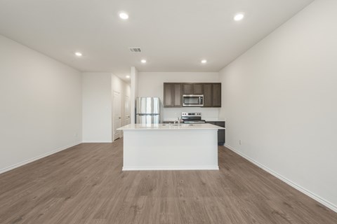 A kitchen with a white countertop and wooden flooring.