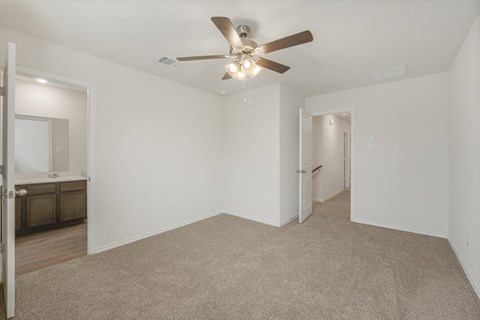 A spacious room with a ceiling fan and carpeted floor.