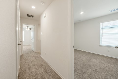 A long hallway with a carpeted floor and white walls.