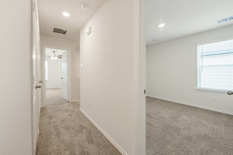 A long hallway with carpeted floors and white walls.