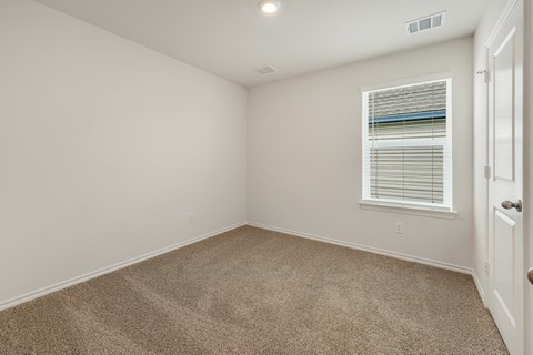 A room with a carpeted floor and a window with blinds.