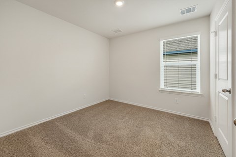 A room with a carpeted floor and a window with blinds.