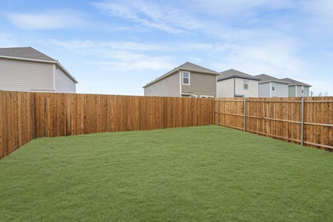 A backyard with a wooden fence and green grass.