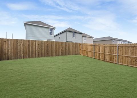 A backyard with a wooden fence and green grass.