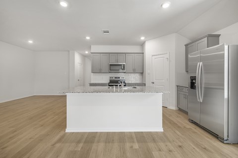 A modern kitchen with stainless steel appliances and wooden flooring.