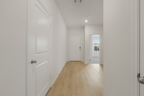 A long hallway with white doors and wood floors.