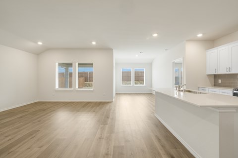 A spacious kitchen and living room with wooden floors and white walls.