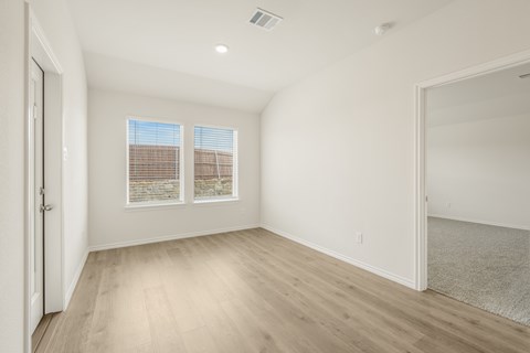 A room with a white wall and a window with blinds.