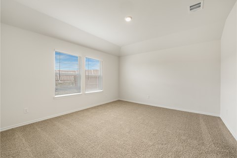 A room with a carpeted floor and two windows.