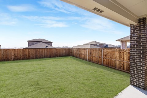 A backyard with a wooden fence and a green lawn.