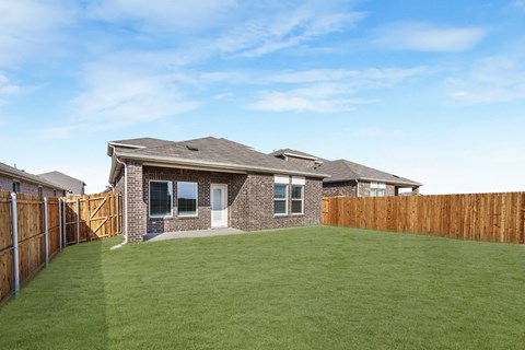 A house with a brown fence and a green lawn.
