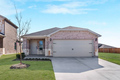 A house with a garage and a tree in front of it.
