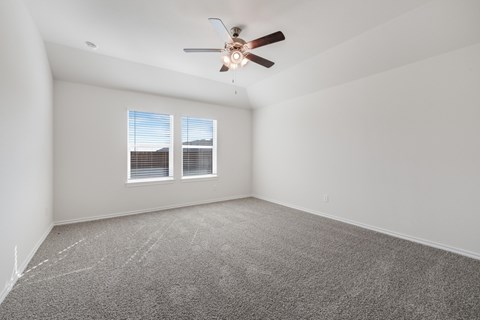 A room with a ceiling fan and carpeted floor.