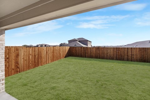 A backyard with a wooden fence and a green lawn.
