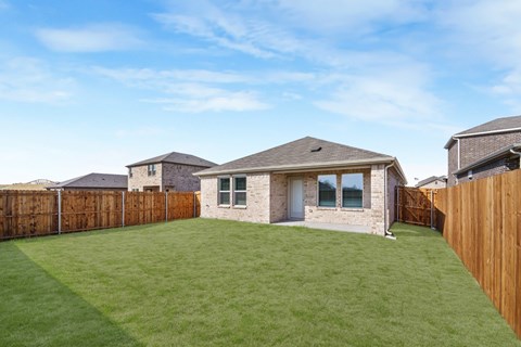 A house with a brown fence and a green lawn.