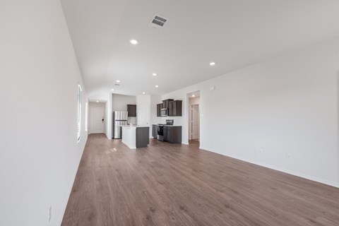 A spacious room with wooden flooring and white walls.