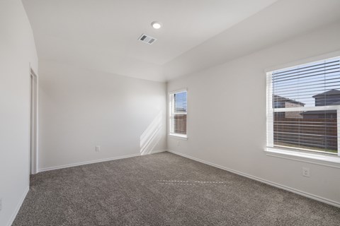 A spacious room with carpeted floor and a window with blinds.