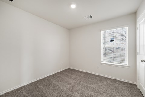 A room with a carpeted floor and a window with blinds.