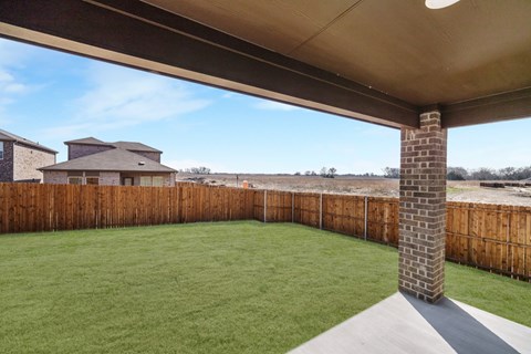 A backyard with a wooden fence and a brick pillar.