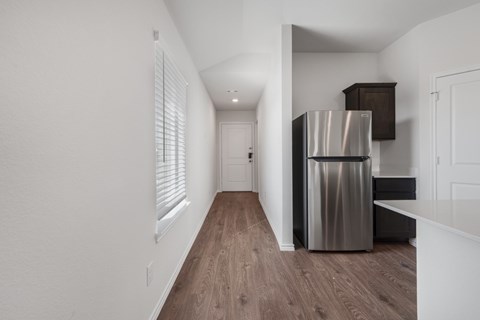 A kitchen with a stainless steel refrigerator and wooden flooring.