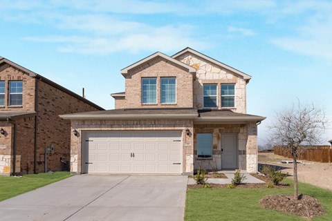 A two-story house with a garage and a tree in front.