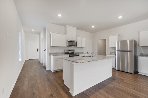 A kitchen with white cabinets and a wooden floor.