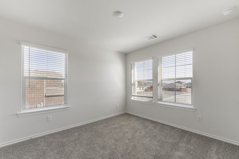 A room with two windows and carpeted floor.