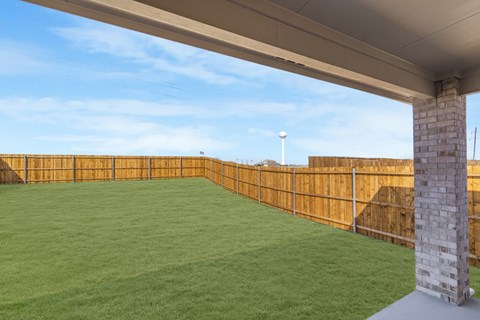A backyard with a wooden fence and a green lawn.