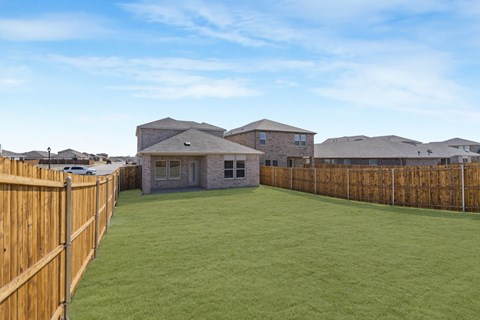 A backyard with a wooden fence and a green lawn.
