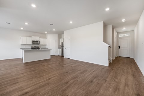 A kitchen with white cabinets and a wooden floor.