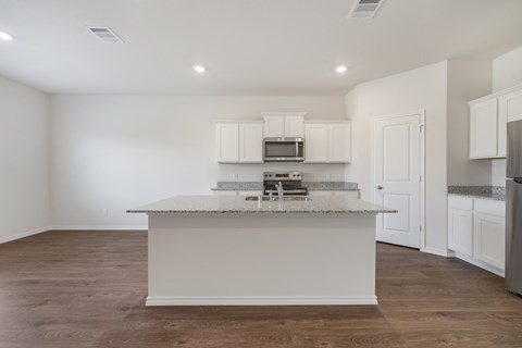 A kitchen with white cabinets and a granite countertop.