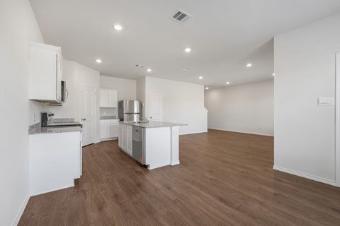 A kitchen with white cabinets and a wooden floor.