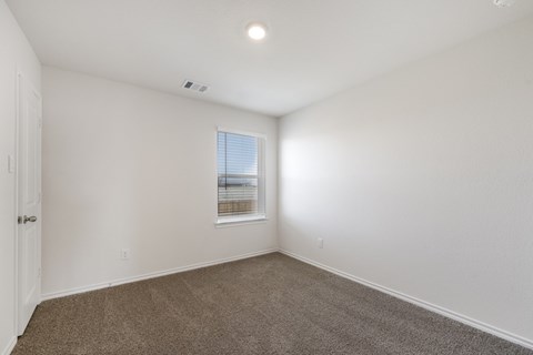 A room with a carpeted floor and a window with blinds.