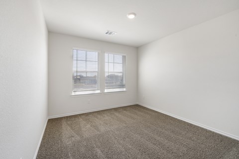 A room with a carpeted floor and a window with blinds.