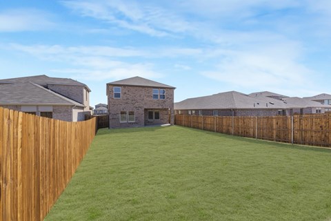 A backyard with a wooden fence and a grassy area.