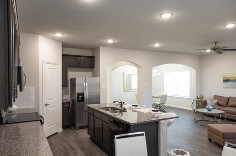 A modern kitchen with a refrigerator, sink, and a dining table with chairs.