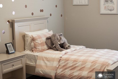 A bedroom with a bed, a teddy bear, and a nightstand.