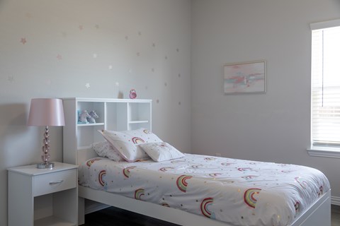 A bedroom with a bed, nightstand, and a window.